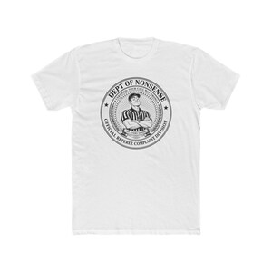 May include: A white short-sleeve t-shirt featuring a black circular graphic on the chest. The design depicts a referee with arms crossed, surrounded by text reading DEPT OF NONSENSE, CERTIFIED: YOUR CALL WAS WRONG, and OFFICIAL REFEREE COMPLAINT DIVISION.