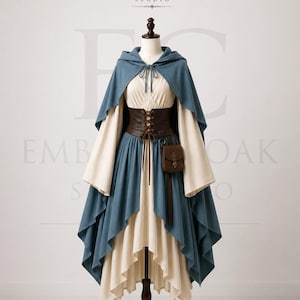 May include: A cream-coloured dress with long, wide sleeves and a high-low hemline, layered under a blue hooded cloak with a front tie. A dark brown corset-style belt with lace-up detailing and a small attached pouch is worn over the dress.