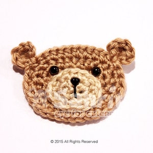 Puede incluir: Aplicación de cara de oso de ganchillo en tonos marrón y crema. El oso tiene ojos negros pequeños y redondos, una nariz negra y orejas pequeñas. La aplicación es probablemente hecha a mano y adecuada para varios proyectos de artesanía.