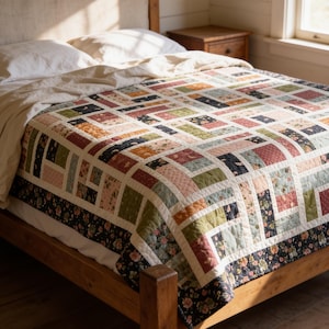 May include: A patchwork quilt featuring a rectangular block pattern in shades of sage green, dusty rose, navy blue, and cream. The quilt is constructed from various floral and solid fabric pieces, finished with a dark floral border along the edges.