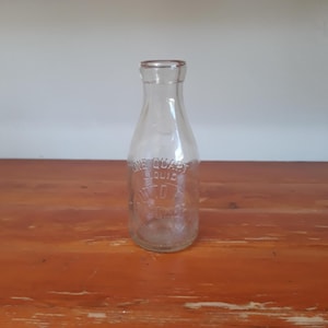 May include: A clear glass bottle with a textured surface. The bottle is labeled "ONE QUART LIQUID" and "AUTO SUGAR"