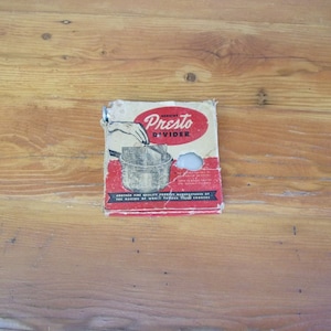 May include: Vintage "Presto Divider" box with red and white text and graphics. The box shows a hand placing a divider into a pot. The box is worn and torn, with the text "Genuine Presto Divider" visible.