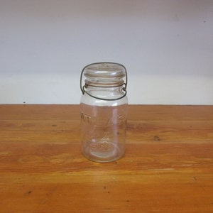 May include: A clear glass jar with a wire bail closure. The jar has the word "ATLAS" embossed on the side.