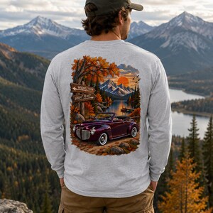 May include: A light gray long-sleeve shirt featuring a graphic print on the back of a dark red vintage convertible car parked near a lake and mountains. The print includes a wooden signpost with the text WRONG TURN and RIGHT PLACE.