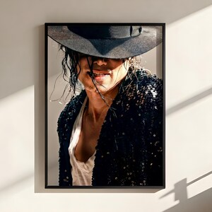 May include: A framed photographic wall art print featuring a person wearing a black fedora hat pulled low over their eyes, a white undershirt, and a black sequined jacket. The person has dark, slightly messy hair and is smiling slightly.