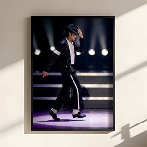 May include: A framed wall art print featuring a performer in a black sequinned jacket, white shirt, black trousers with a white side stripe, and a black fedora hat. The figure is captured in a dynamic dance pose on a stage with purple lighting.