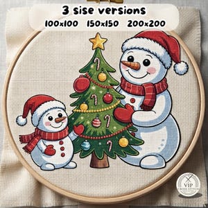 May include: A cross-stitch pattern in a wooden hoop featuring two snowmen decorating a green Christmas tree with red and yellow ornaments, candy canes, and a yellow star. Text at the top reads 3 sise versions 100x100 150x150 200x200.