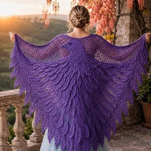 May include: A vibrant purple crochet shawl featuring an intricate bird design with detailed feather-like textures across the back. The garment has a wide, wing-like span and a delicate open-knit pattern along the upper shoulders and neckline.