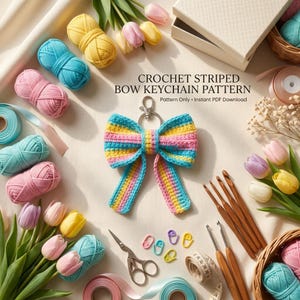 May include: A crochet striped bow keychain with blue, yellow, and pink horizontal stripes, featuring a metal clasp. The image includes yarn balls, wooden crochet hooks, scissors, stitch markers, a measuring tape, and tulip flowers.