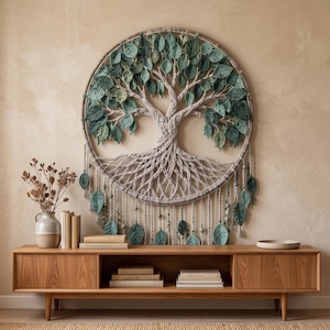 May include: A large circular wall hanging featuring a macrame tree of life design with intricate knotted branches and roots. The tree is adorned with numerous fabric leaves in various shades of green, with additional leaf accents hanging below.