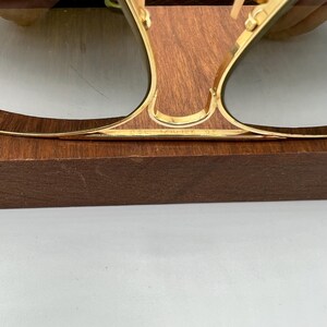K&ouml;nnte beinhalten: Goldfarbene Aviator-Sonnenbrille mit einem braunen Holzst&auml;nder. Die Sonnenbrille hat einen Metallrahmen und gr&uuml;ne Gl&auml;ser. Der Text "B&L RAY-BAN U.S.A." ist in den Rahmen graviert.