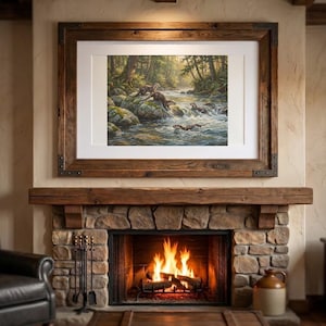 May include: A framed landscape painting depicting a group of otters playing in a rocky river surrounded by a lush forest. The artwork is encased in a wide, rustic dark wood frame with metal corner accents, mounted above a stone fireplace.