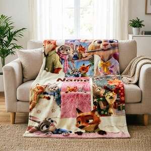 May include: A soft fleece throw blanket featuring a collage of Zootopia characters including Judy Hopps and Nick Wilde in various scenes. The blanket includes a central rectangular section with the printed text Name and colourful illustrations.