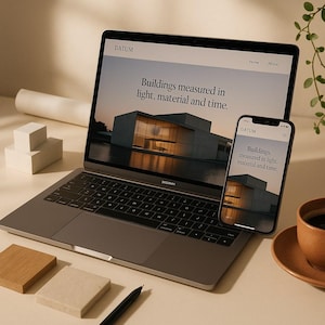 Puede incluir: Un portátil gris oscuro y un teléfono inteligente que muestran un sitio web con el texto "DATUM" y "Buildings measured in light, material and time." Las pantallas muestran un edificio moderno al atardecer. Los dispositivos están sobre una superficie clara.
