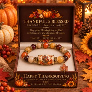 May include: A beaded bracelet with faceted orange, yellow, and dark red stones, featuring a central barrel bead with a turkey illustration and a maple leaf charm, presented in a brown box with Thanksgiving text and autumn harvest graphics.
