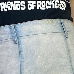 May include: A pair of light blue denim jeans with a light wash. The jeans have a button fly and belt loops. The jeans are worn and have a faded appearance.