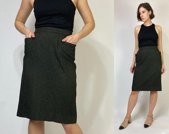 May include: A dark green skirt with a textured pattern and two pockets. The skirt is knee-length and has a straight silhouette.
