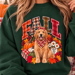 May include: A dark green crewneck sweatshirt featuring a graphic of a golden retriever wearing a red plaid bandana and bow. The design includes the word FALL in plaid letters, pumpkins, autumn leaves, berries, and a sign reading HELLO FALL.