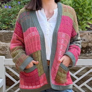 Peut inclure: Un cardigan en tricot à manches longues présentant un motif patchwork composé de panneaux rose, vert olive et vert foncé. Le vêtement possède une encolure en V, une bordure côtelée vert foncé sur l'ouverture, les poignets et l'ourlet.