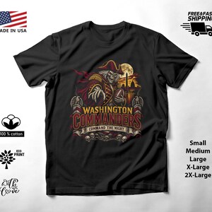 May include: A black t-shirt featuring a graphic of a skeleton dressed as a pirate holding a football. The text reads WASHINGTON COMMANDERS COMMAND THE NIGHT. The design includes a full moon, a city skyline, and skulls at the bottom of the print.