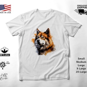 May include: A white short-sleeved t-shirt featuring a watercolor-style graphic of a brown and black wolf head on the chest. The design includes splashes of orange and dark tones, centered on the fabric. The shirt has a crew neckline and short sleeves.