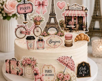 May include: A round white frosted cake decorated with various Paris-themed paper toppers including the Eiffel Tower, a pink bicycle, a cafe, a poodle, a suitcase, macarons, a croissant, a perfume bottle, and signs reading Paris, Bonjour, and Ooh la la.