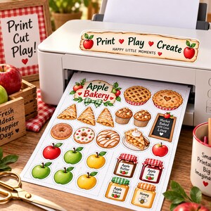Może przedstawiać: Biała drukarka drukująca arkusz naklejek z ilustracjami Apple Bakery, w tym ciastami, babeczkami, pączkami, jabłkami oraz słoikami z etykietami Apple Butter, Apple Jam, Apple Sauce i Honey. Arkusz zawiera napis Print Play Create.