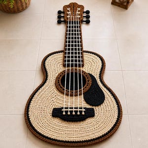 Könnte beinhalten: Ein gitarrenförmiger Teppich aus gehäkeltem Garn in Beige, Braun und Schwarz. Das Design zeigt ein detailliertes Griffbrett mit weißen Garnsaiten, ein kreisförmiges Schallloch, ein schwarzes Schlagbrett und einen Steg aus strukturiertem Textil.