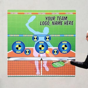 May include: A green and white illustrated sign with the text "Your Team, Logo, Name Here" and the words "Too High" and "Stay Below" repeated multiple times. The sign shows a silhouette of a person playing pickleball with a paddle and a ball. The sign also shows a net and four targets with the word "Dink" on them.