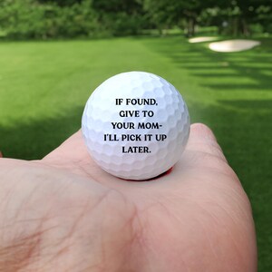May include: A white golf ball with black text that reads "If found, give to your mom - I'll pick it up later."