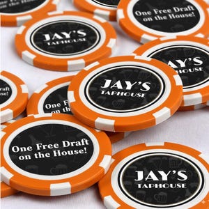 May include: Orange and white poker chips with the text "JAY'S TAPHOUSE" and "One Free Draft on the House!" printed on them. The chips have a black center with beer-related graphics.