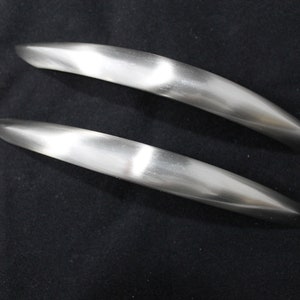 May include: Two silver-toned cabinet door pulls with a curved design.