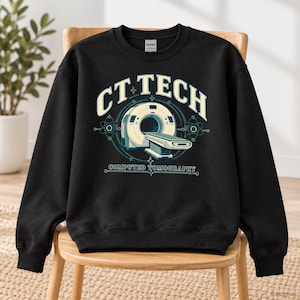 Könnte beinhalten: Ein schwarzes Sweatshirt mit Rundhalsausschnitt und einem Grafikdruck eines CT-Scanners. Der Text CT TECH ist in einer hellen Cremefarbe über der Maschine gewölbt, mit den Worten COMPUTED TOMOGRAPHY in kleinerer Schrift unter der Abbildung.