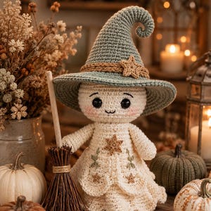 May include: A crocheted doll wearing a sage green pointed hat with a tan band and star accent. The doll has a cream-colored dress featuring embroidered stars and green sprigs. It holds a small brown twig broomstick. The doll has black eyes.
