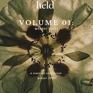 May include: A book cover featuring a large, translucent, sepia-toned flower with dark central markings. The text reads: held, VOLUME 01: winter notes, a seasonal companion, winter 2026. A small H logo is visible in the centre and bottom right corner.