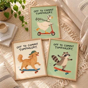 May include: Three framed wall art prints featuring animals on wheels with the text OFF TO COMMIT TOMFOOLERY. One print shows a goose on a red scooter, another a dog on a blue skateboard, and the third a raccoon on a red skateboard.
