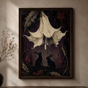 May include: A framed rectangular wall art print featuring a large, pale, bell-shaped flower hanging downward above two dark, silhouetted rabbits sitting on a textured ground. The background is a deep, moody purple and black with subtle foliage.