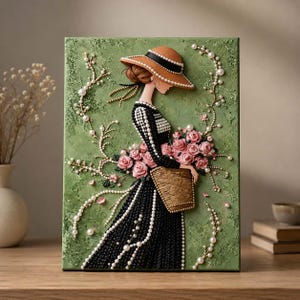 May include: A textured green wall art piece featuring a three-dimensional figure wearing a wide-brimmed tan hat and a black dress adorned with white pearls. The figure holds a basket filled with pink roses, surrounded by delicate pearl vine accents.