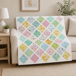 May include: A patchwork quilt featuring a diamond-patterned design with various pastel-colored fabric squares in shades of yellow, pink, blue, and green. The quilt is constructed with white fabric borders between each square, creating a grid-like layout.