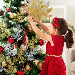 May include: A set of artificial glittery gold and silver pine branch decorations attached to a green Christmas tree. The branches feature a textured, sparkling finish and are arranged among various round red and gold ornaments on the tree.