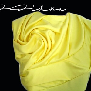 May include: A bright yellow fabric draped and folded into a rose shape.