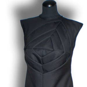 May include: A black sleeveless dress with a geometric design on the bodice. The dress is fitted and has a straight skirt.