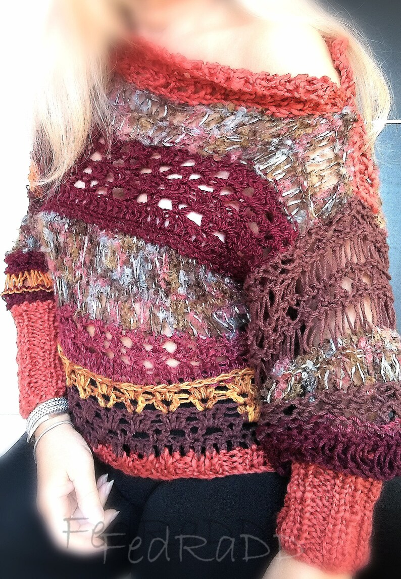 May include: A handmade, open-weave sweater in shades of burgundy, rust, and gold. The sweater features a unique crochet design with a textured, multi-colored yarn. The sleeves and neckline have a ribbed knit detail. A stylish, bohemian-inspired garment.
