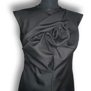May include: A black sleeveless dress with a large, gathered fabric detail at the neckline.
