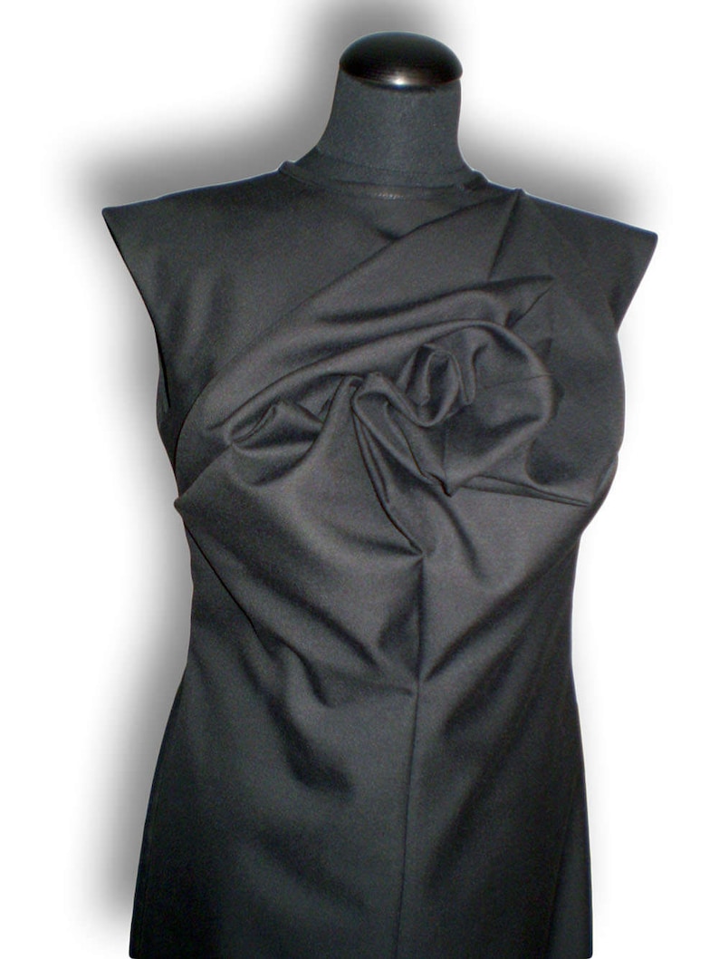 May include: A black sleeveless dress with a large, gathered fabric detail at the neckline.