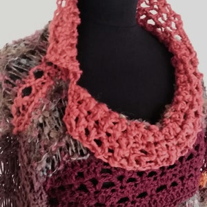 May include: A handmade, multi-colored crochet cowl and shawl set. The cowl is a vibrant coral color, while the shawl features a mix of burgundy, gray, and coral hues. The text "Fed Ra DD" is visible in the upper left corner.