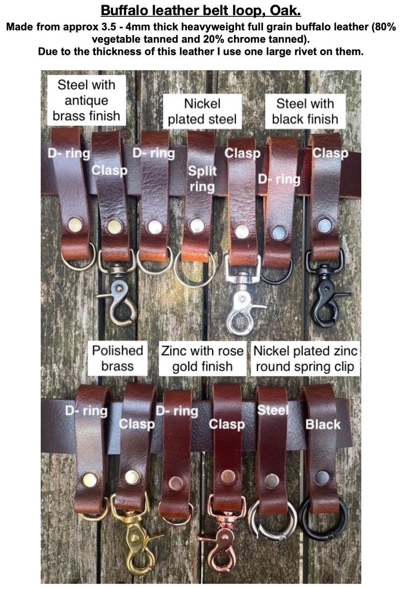 May include: A collection of oak-coloured buffalo leather belt loops, each secured with a single large rivet. The loops feature various metal hardware attachments including D-rings, clasps, split rings, and spring clips in antique brass, nickel, black, and rose gold finishes.