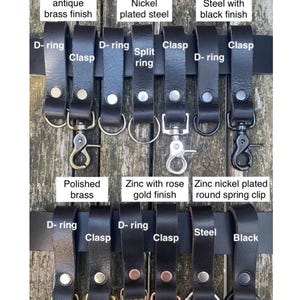 May include: Black buffalo leather belt loops, 3.5-4mm thick, secured with a single large rivet. Features various metal hardware attachments including D-rings, clasps, split rings, and spring clips in antique brass, nickel, black, and rose gold finishes.