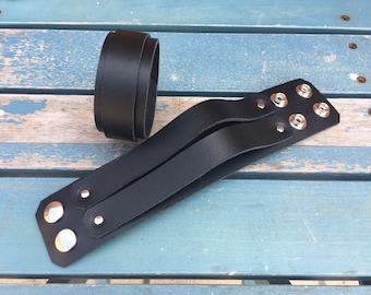 May include: A black leather bracelet with two straps and silver metal studs.