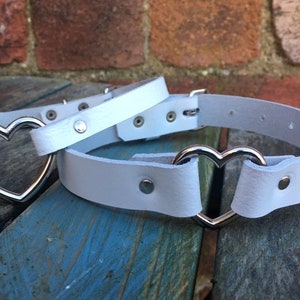 May include: White leather choker with a silver heart-shaped buckle.